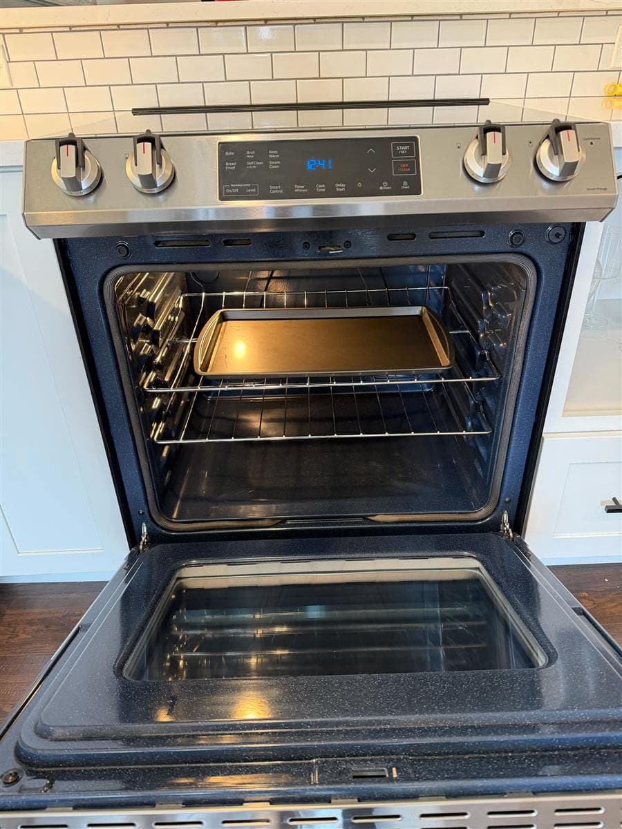 An oven caked in baked-on soot and grease cleaned to a mirror shine by a New Jersey house cleaning team.