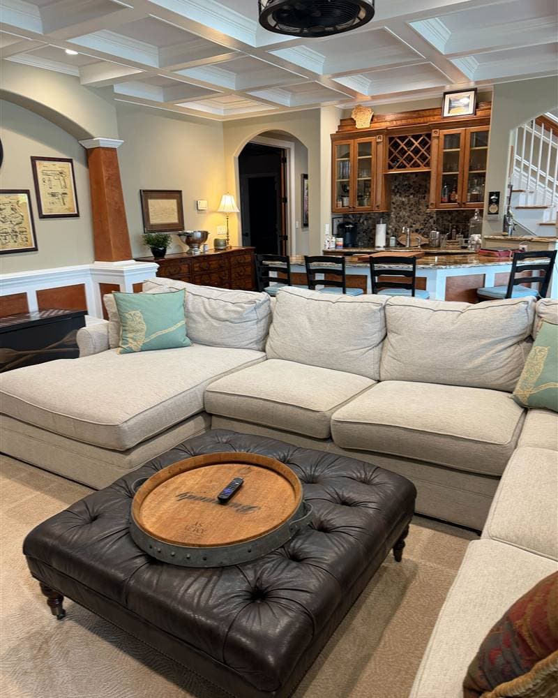 A tidy, spacious living room with a wet bar and coffered ceiling, cleaned by a New Jersey house cleaning service.