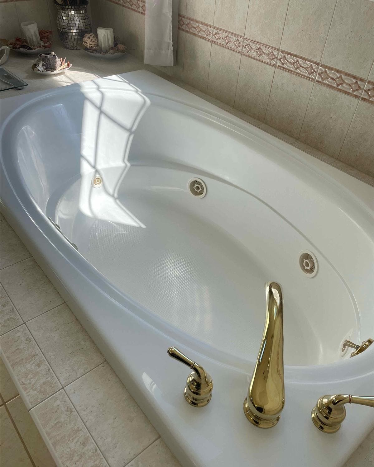 Sparkling clean white jetted bathtub with polished gold fixtures after a deep cleaning in Jefferson, NJ