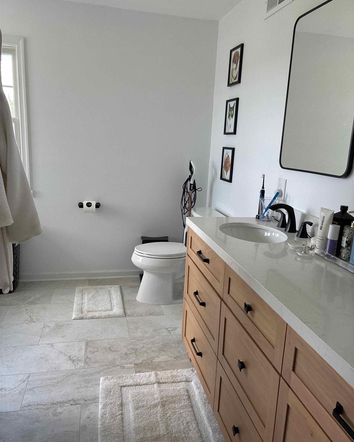 Freshly cleaned modern bathroom with wood vanity, quartz countertop, and large mirror after a residential cleaning in Newton, NJ